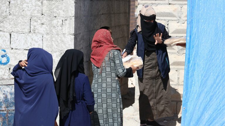 Frauen bilden eine Kette und reichen Pakete weiter.