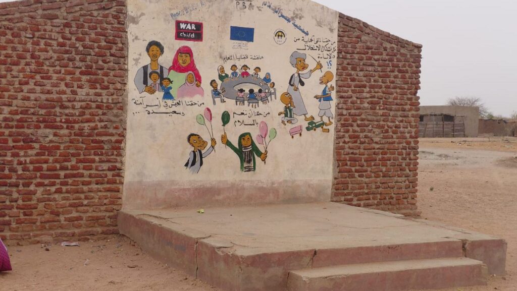 Die Wand von einem Backsteinhaus hat in der Mitte eine glatte Fläche auf der mit Kreide bemalt wurde