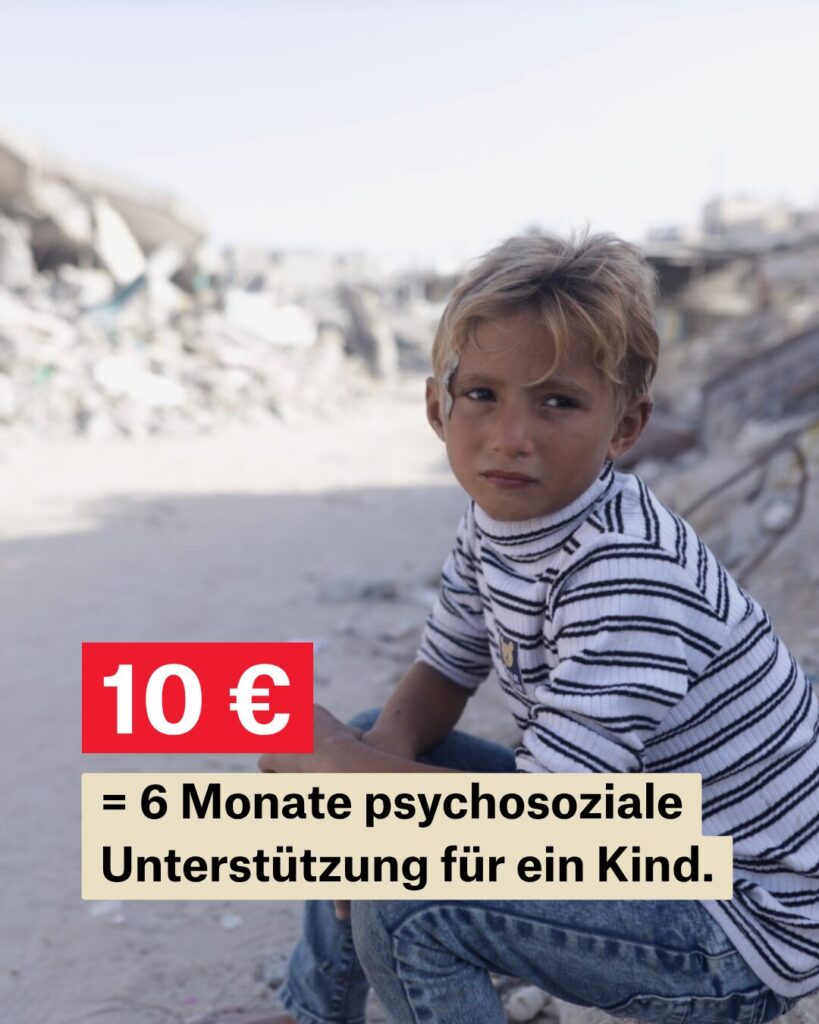 Ein blonder Junge im gestreiften Shirt sitzt auf dem Boden und schaut erschöpft. Im Hintergrund ins eine sind riesige Trümmerberge.